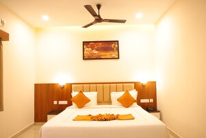 Habitación de hotel con cama, ventilador de techo, un cuadro y lámparas de noche.