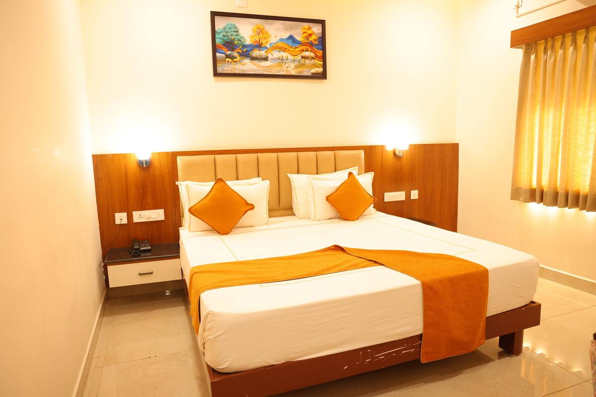 Quarto de hotel com cama, mesa de cabeceira e uma pintura na parede.