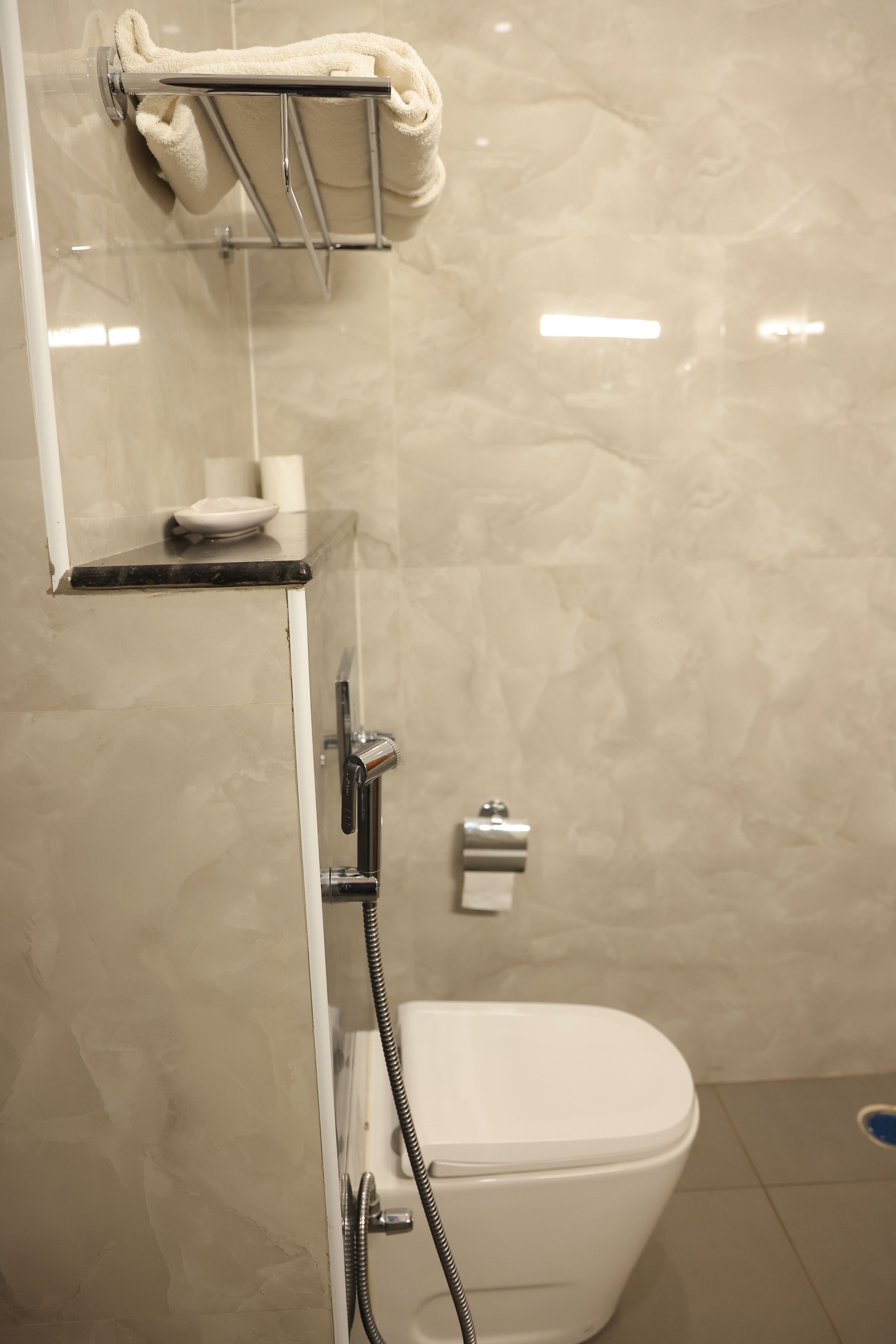 A bathroom with a toilet, a towel rack, and a soap dish.