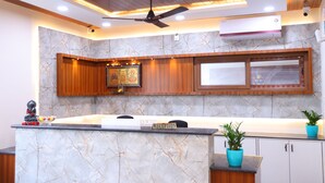 A reception area with a marble counter, wooden cabinets, a ceiling fan, and a wall-mounted air conditioner. - Nanda Mohan Residency (Tirupati)