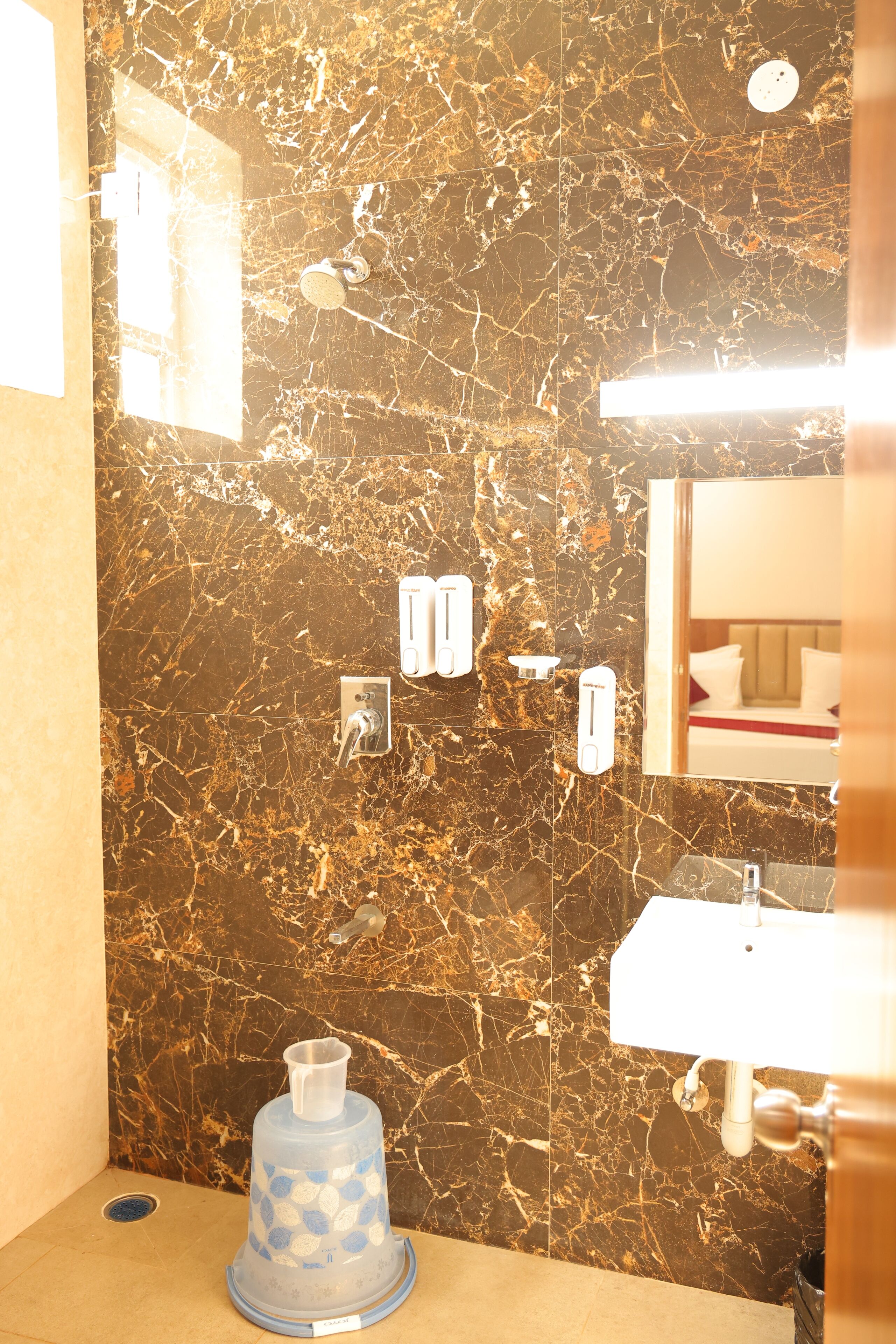 A bathroom with a marble wall, a sink, and a hand dryer.