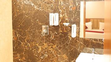 A bathroom with a marble wall, a sink, and a hand dryer.