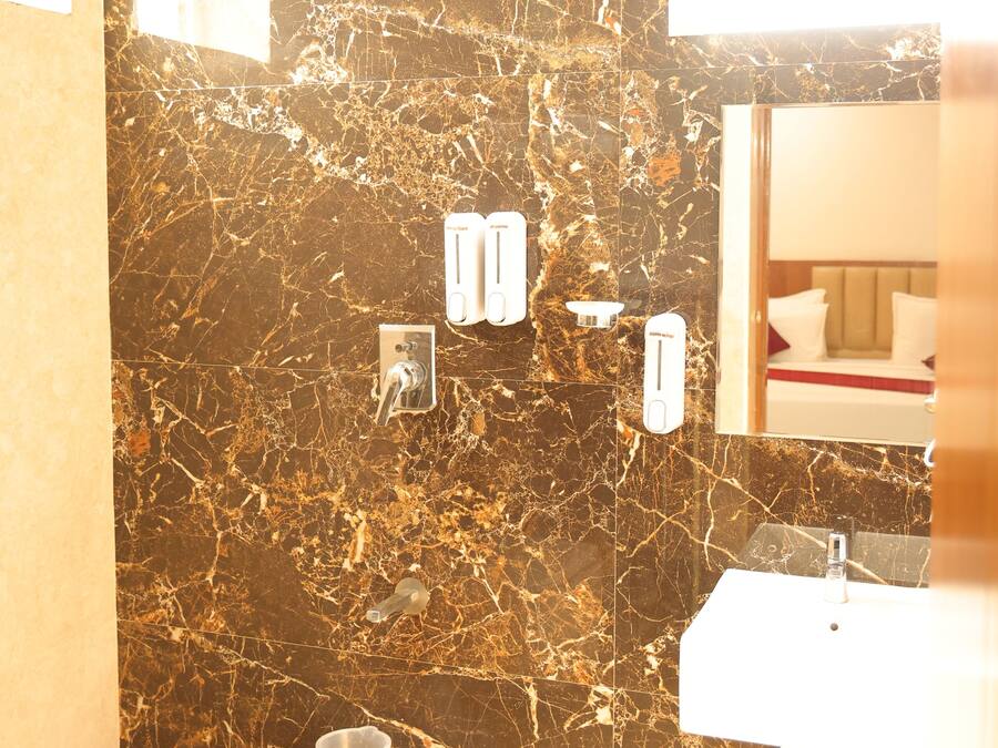 A bathroom with a marble wall, a sink, and a hand dryer.