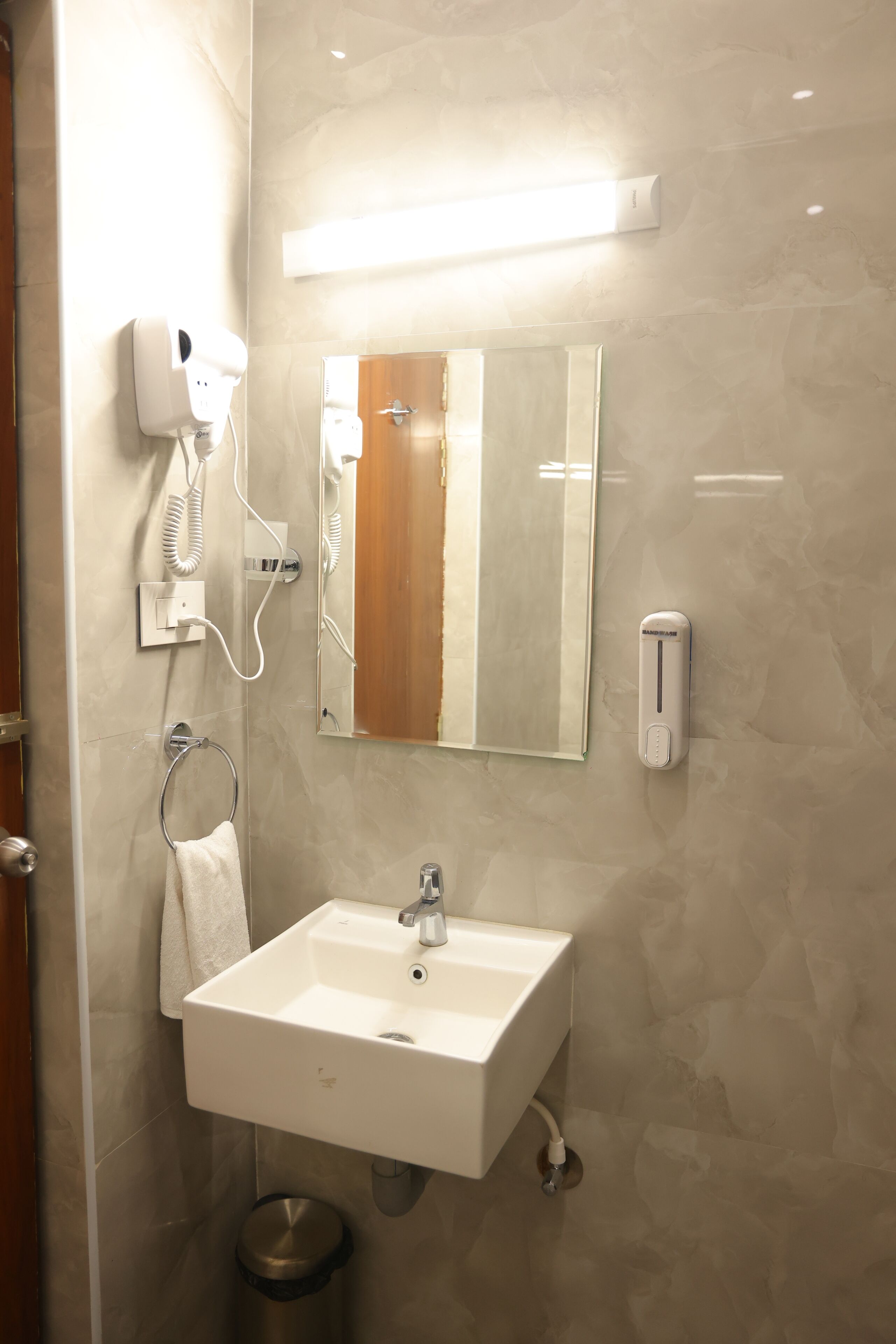 A bathroom with a sink, mirror, towel rack, and a hand dryer.