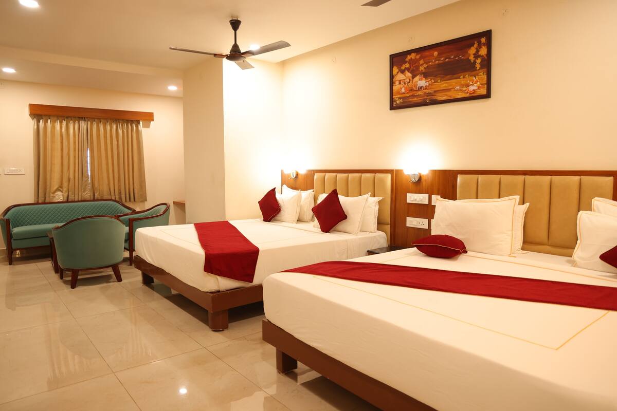 Quarto de hotel com duas camas, um ventilador de teto, um quadro na parede e uma janela com cortinas.