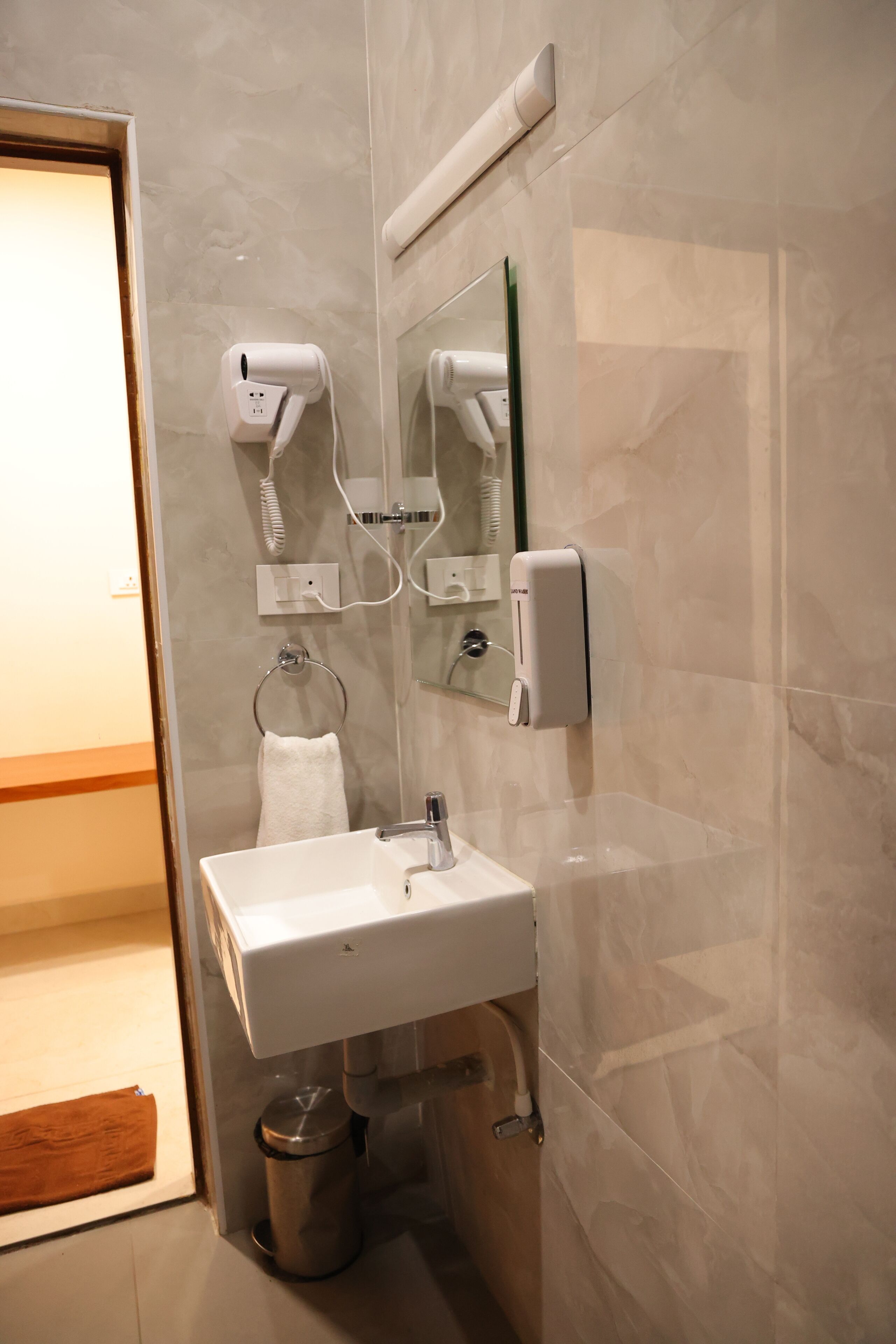 Un baño con lavabo blanco, toallero, secador de pelo y secamanos.