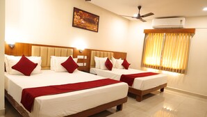 A hotel room with two beds, a ceiling fan, an air conditioner, and a window with curtains. - Nanda Mohan Residency (Tirupati)