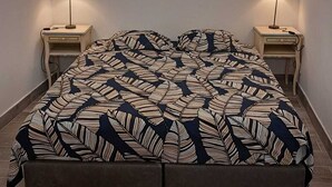 A bedroom with a bed, two bedside lamps, a ceiling fan, and a patterned bedspread.