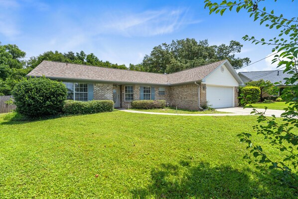 A single-story house with a brick exterior, a garage, and a well-maintained lawn. - Tranquil Haven | Pet Friendly (Pensacola)