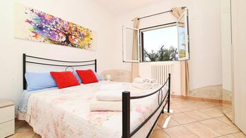 Quarto com uma cama, janela, radiador e um quadro na parede.