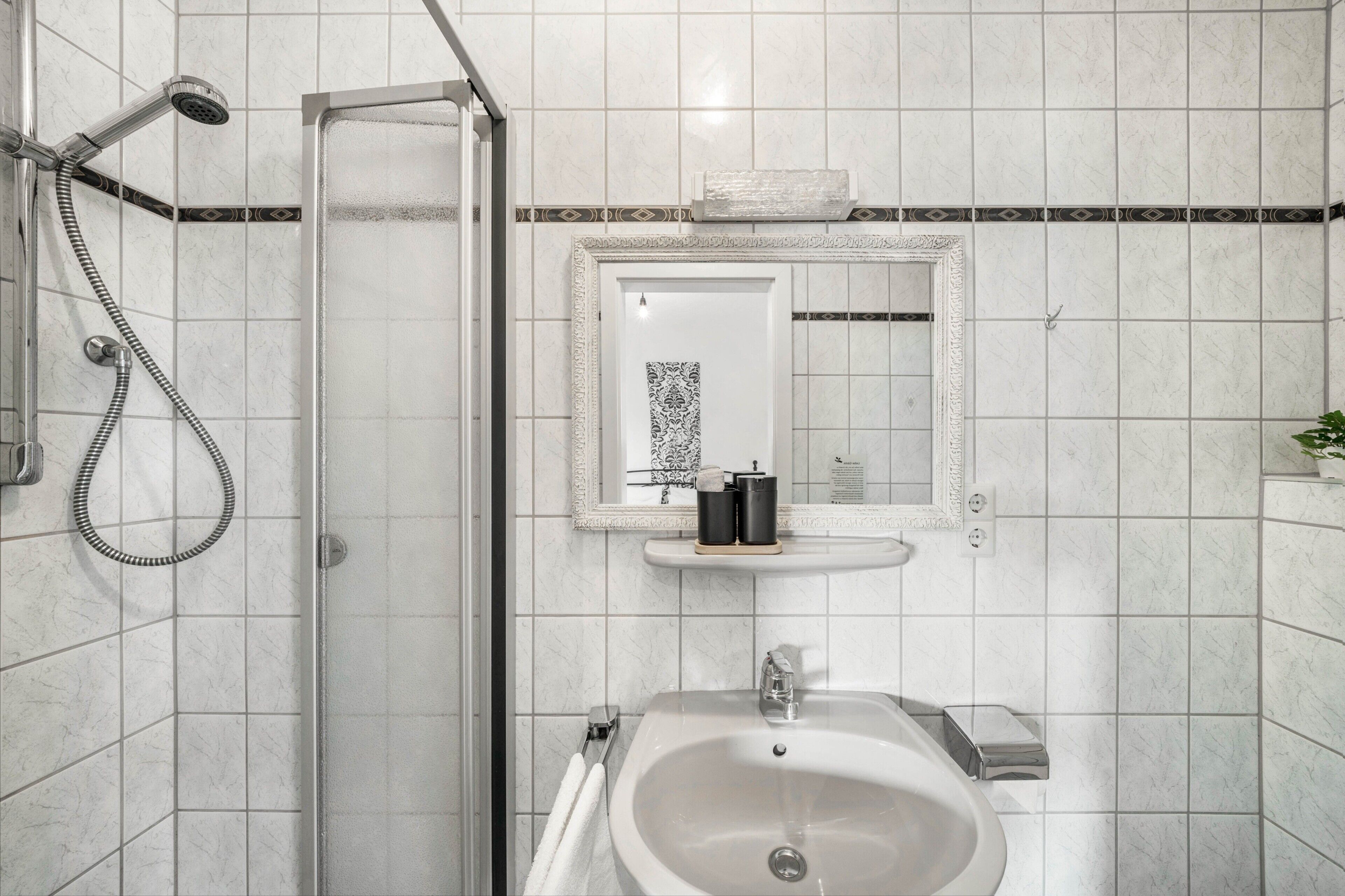 Un baño con ducha, lavamanos y espejo.
