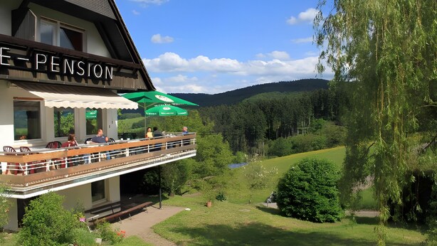 A building with a sign reading 'E-PENSION' and a balcony with outdoor seating. - Zimmer Nr. 1 mit privatem Balkon, Gartenmitbenutzung und WLAN (Mühlenbach)