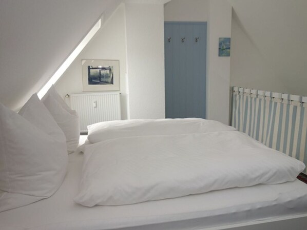 Une chambre à coucher avec un lit, des murs blancs, une porte bleue et un radiateur.
