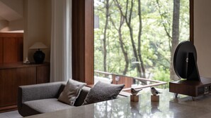 Ein modernes Wohnzimmer mit großem Fenster, einer Couch, einem Tisch mit Dekoration und einem Holzschrank.