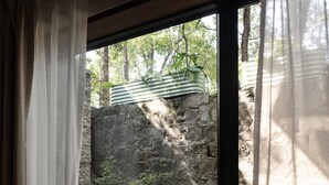 Ein Zimmer mit großem Fenster, Steinwand und einer hölzernen Bank.