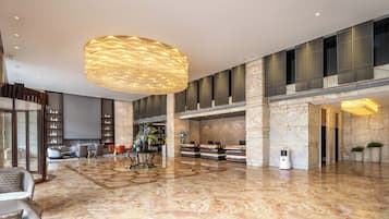 Un hall d’entrée spacieux, agrémenté d’un grand lustre, d’un sol en marbre et d’un comptoir d’accueil.