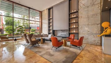 A modern interior with a seating area, a fireplace, and a large window overlooking a cityscape.