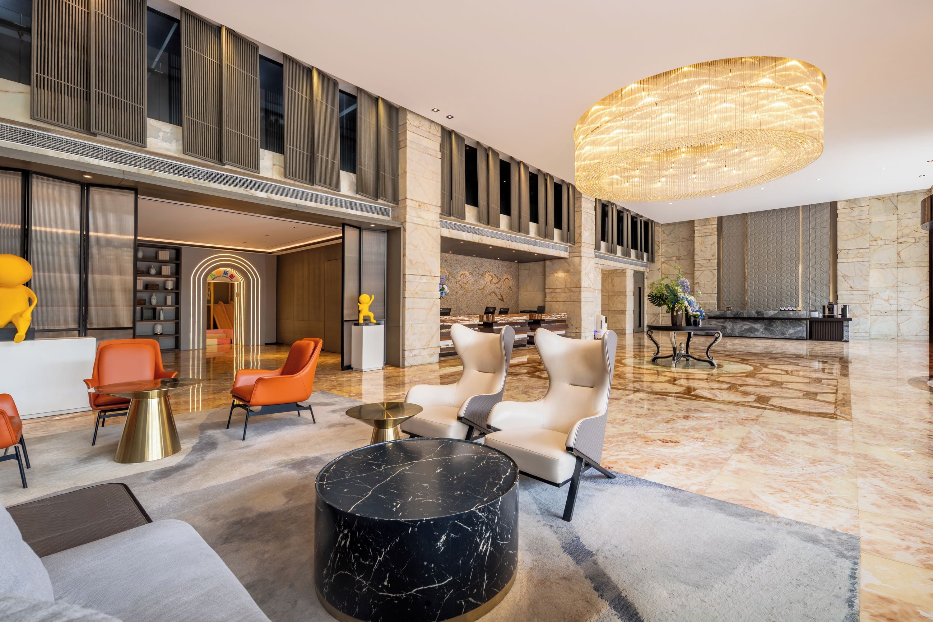 A spacious lobby with a high ceiling, modern furniture, and a large chandelier.