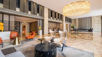 A spacious lobby with a high ceiling, modern furniture, and a large chandelier.