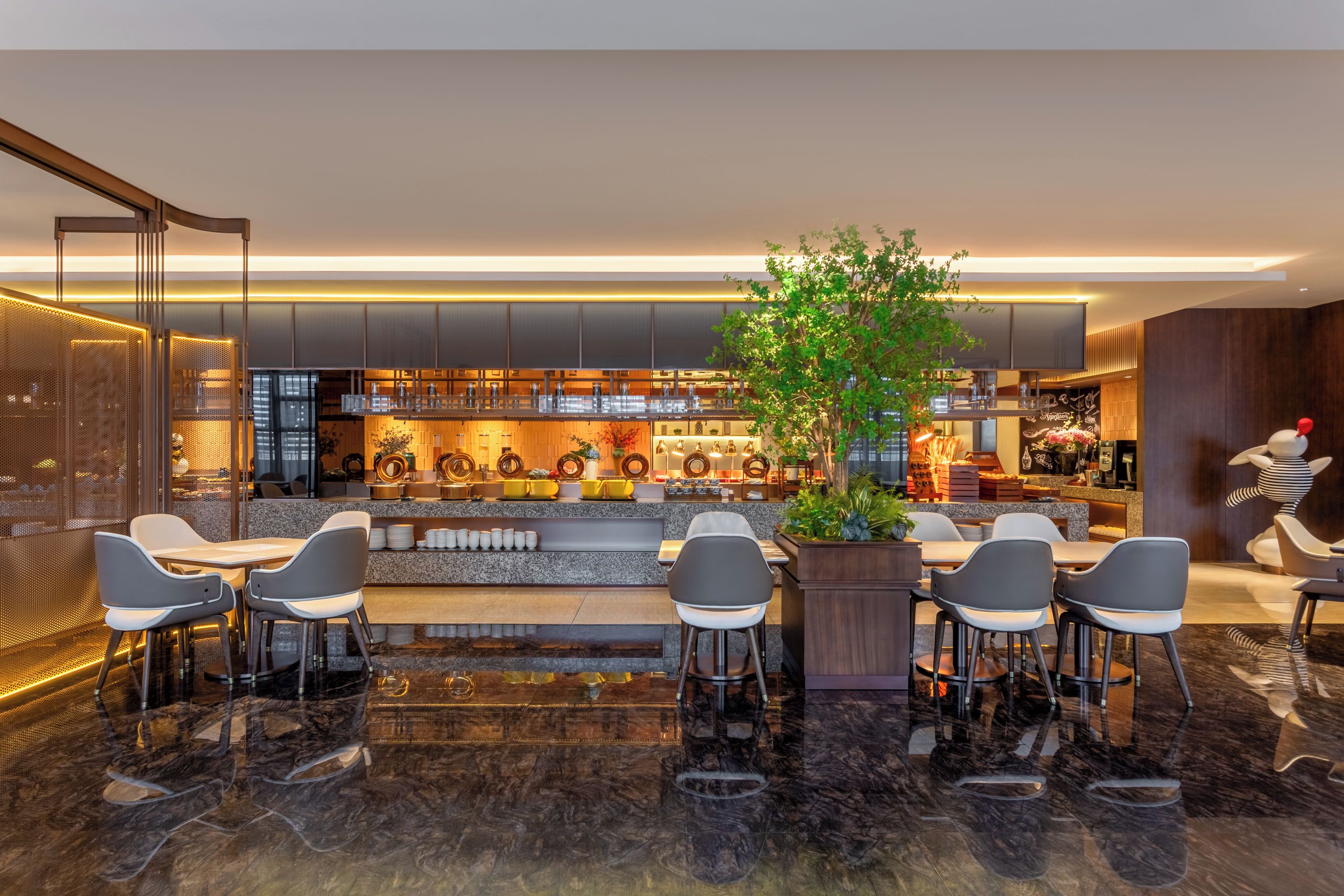 A modern bar area with a seating arrangement, a large plant, and a bar counter with various items.