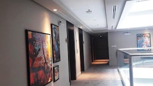 Un couloir orné d’œuvres d’art aux murs, doté d’une rambarde en verre et d’un sol à motifs.