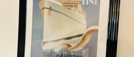 Une affiche encadrée représentant un navire de la compagnie Atlantic Line, avec le texte suivant : « Southampton – New York – Queen of the Ocean – Traversées hebdomadaires ».
