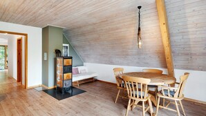 Un comedor con mesa y sillas de madera, techo de madera y una lámpara.