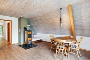 A dining area with a wooden table and chairs, a wooden ceiling, and a light fixture.