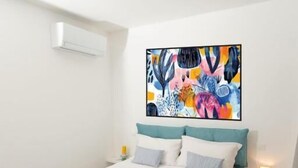 A modern hotel room with a large bed, white walls, and a colorful abstract painting above the bed. - Blu Arechi Camere di Charme - Salerno (Salerno)