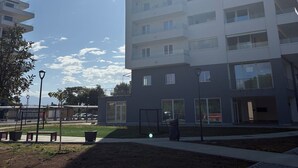 A modern multi-story residential building with balconies, a paved area with benches, and a clear sky. - Blu Arechi Camere di Charme - Salerno (Salerno)