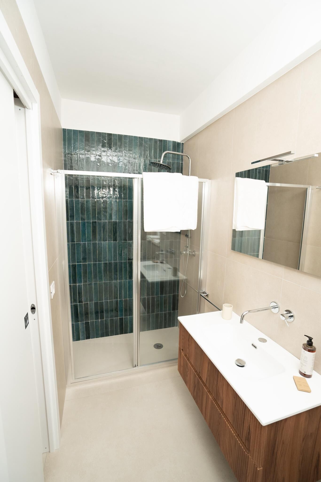 A modern bathroom with a glass-enclosed shower, a wooden vanity, and a large mirror.