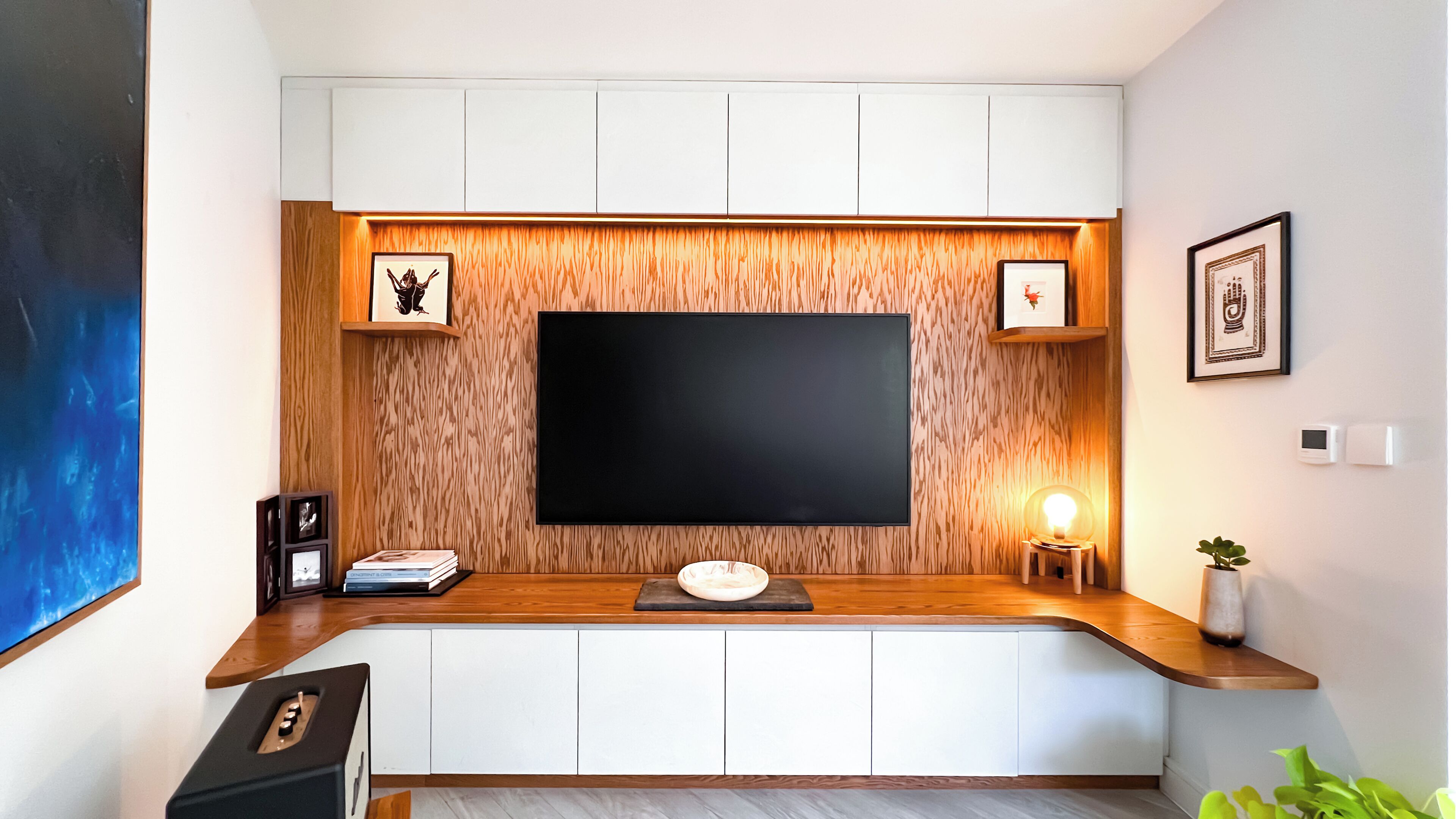 Un salon moderne avec un téléviseur à écran plat, un mur d’accent en bois et une petite table d’appoint avec une lampe.
