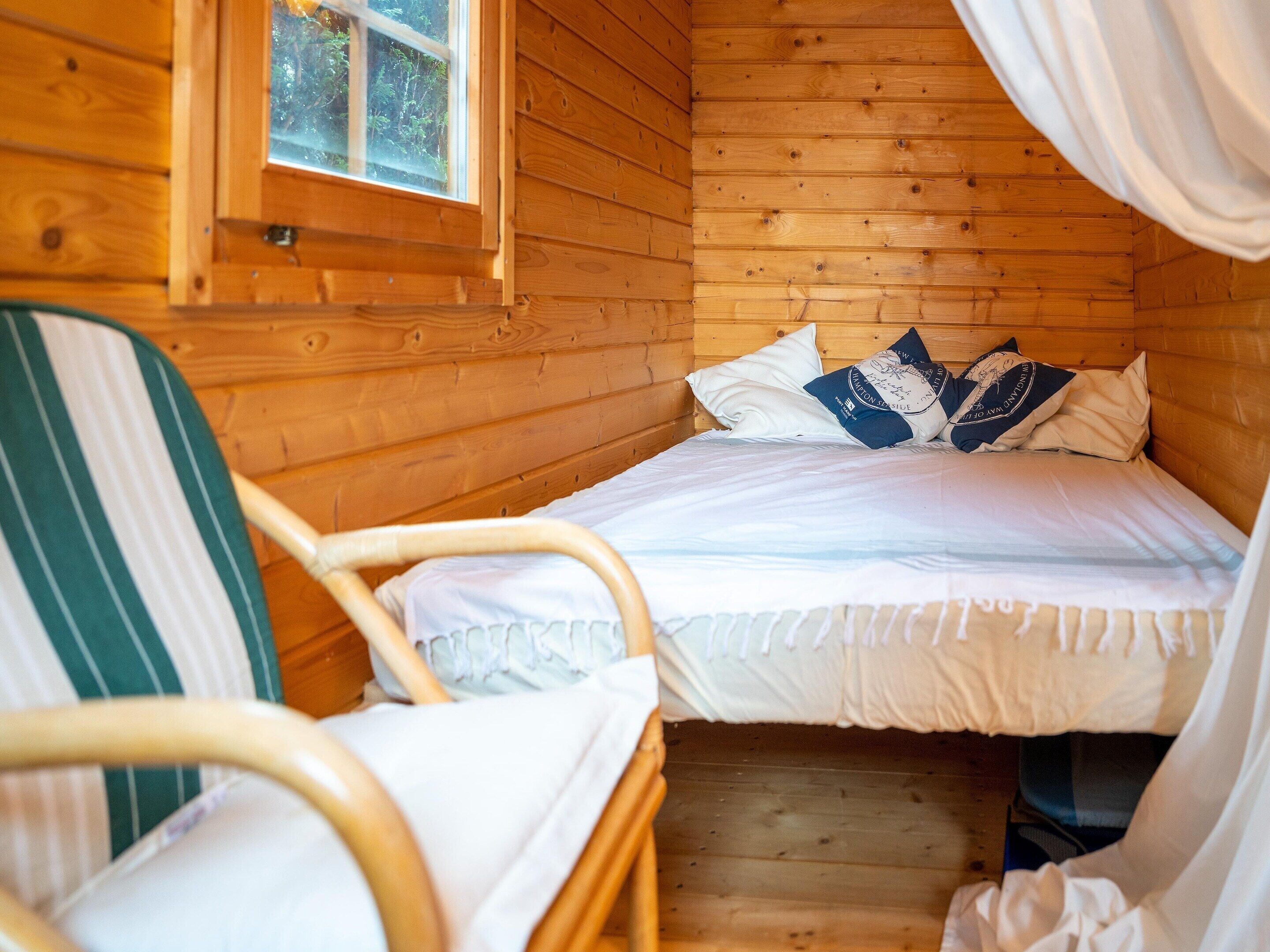 Una camera da letto in legno con un letto, una sedia e una finestra.