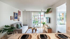 En moderne stue med spiseplads, en grå sofa, et sofabord og et stort vindue med udsigt ud