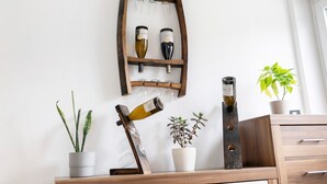 Een wijnrek met flessen en glazen, een potplant en een houten plank.
