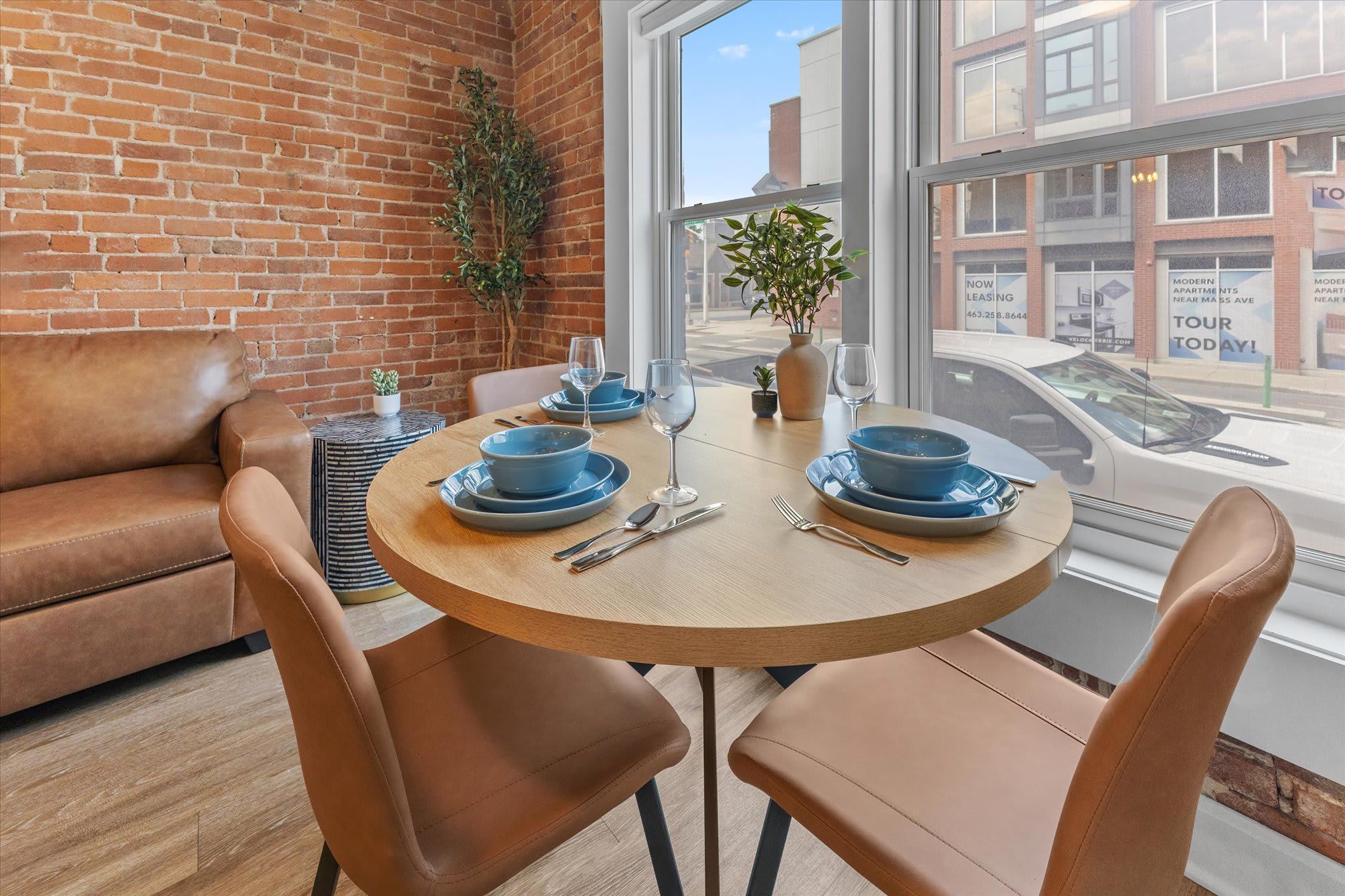A dining area with a round table, brown leather chairs, and blue plates.