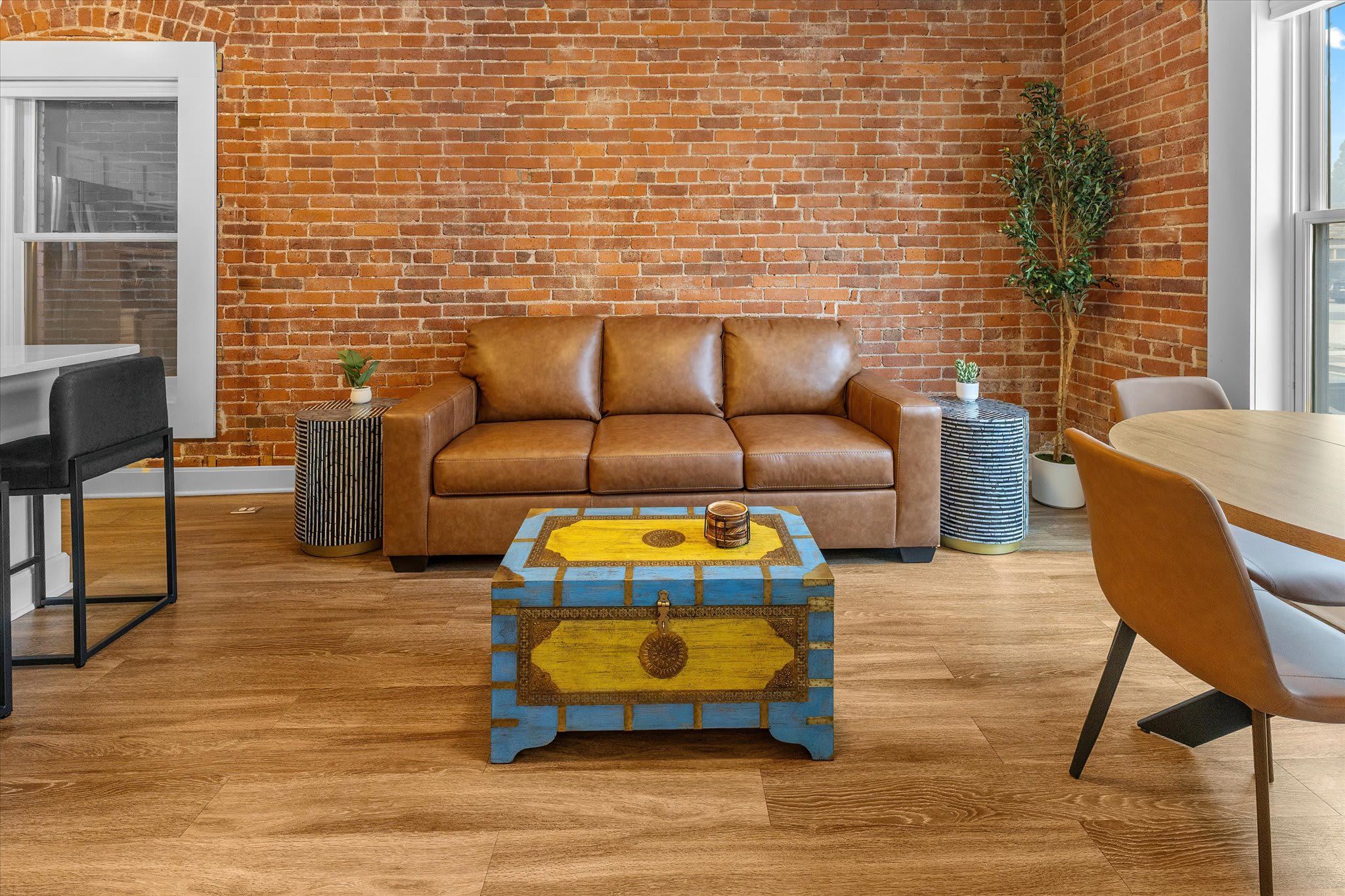 A cozy room with a leather sofa, a wooden coffee table, and a brick wall.