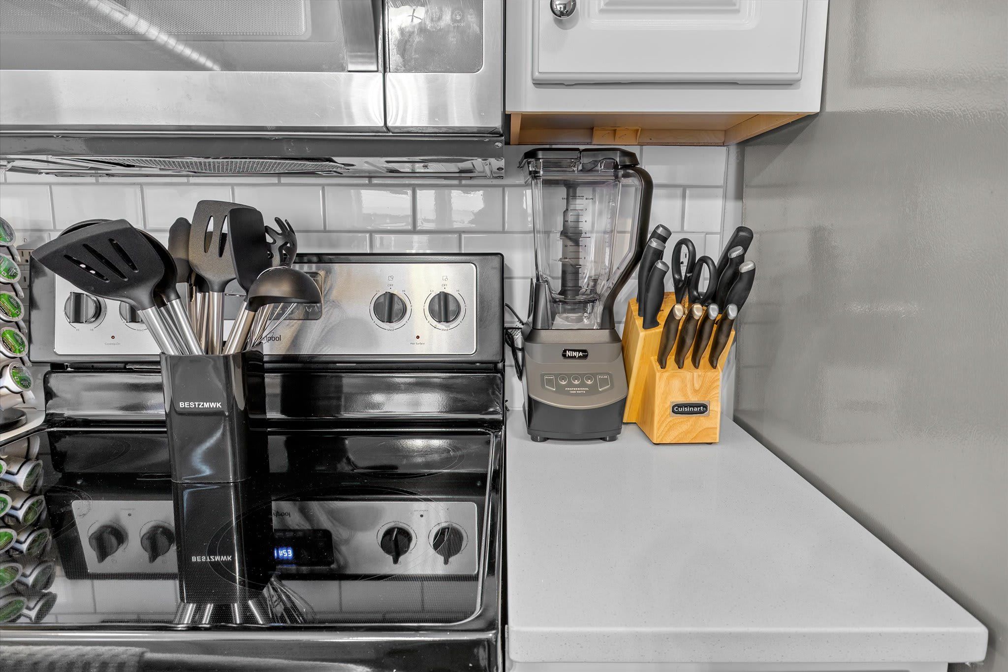 A kitchen with a stove, blender, and knife block.
