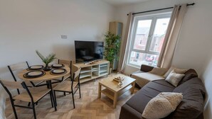 Ein modernes Wohnzimmer mit Sofa, Couchtisch, Fernseher und Essbereich.