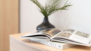 Eine offene Zeitschrift auf einer Holztischplatte, neben ihr ein Buch mit dem Titel "LIVE BEAUTIFUL".