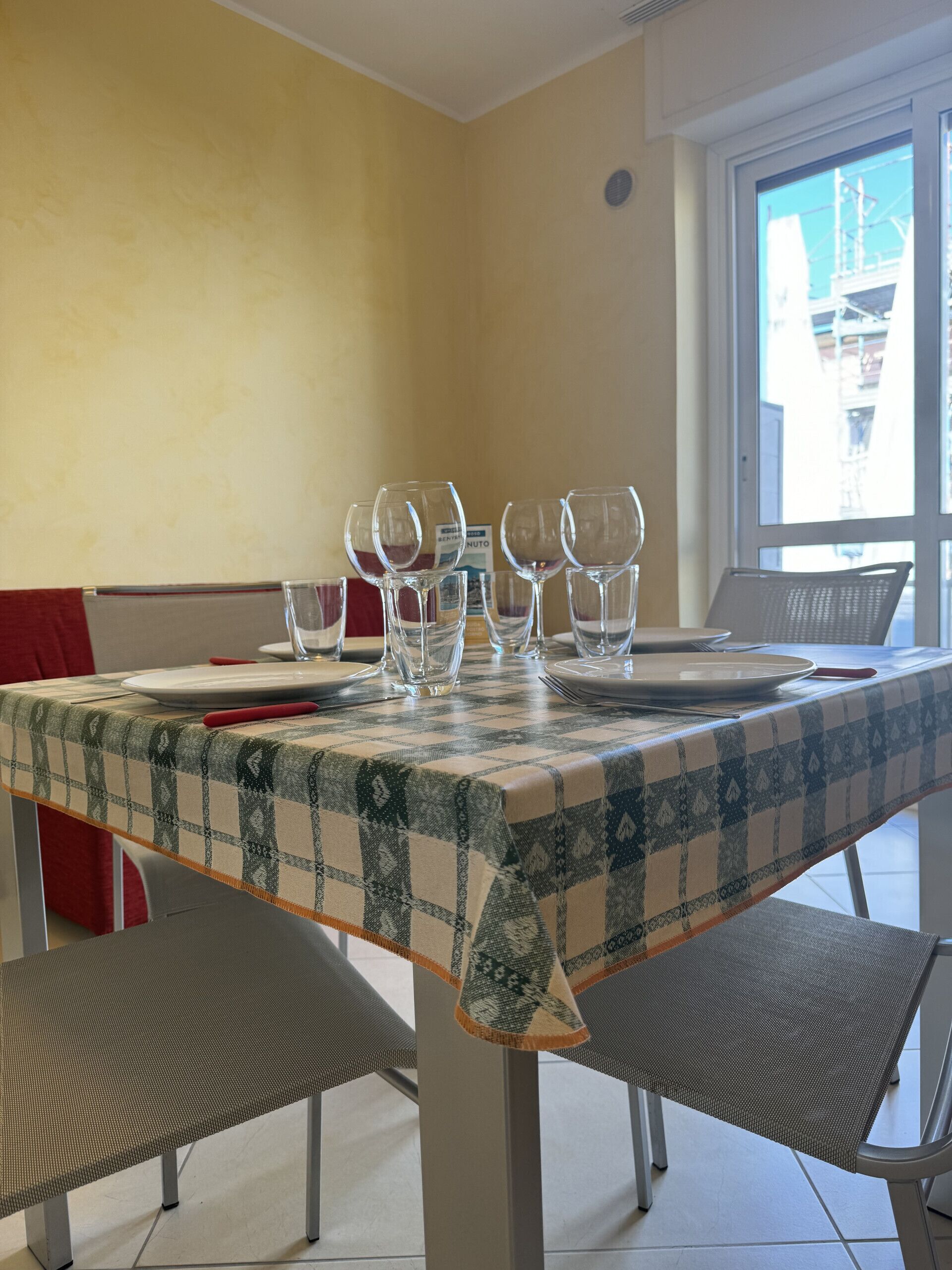 A dining table with a checkered tablecloth, several empty wine glasses, and a few plates.