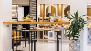 A modern breakfast bar with a variety of food items, a coffee machine, and a decorative plant.