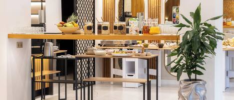 A modern breakfast bar with a variety of food items, a coffee machine, and a decorative plant.