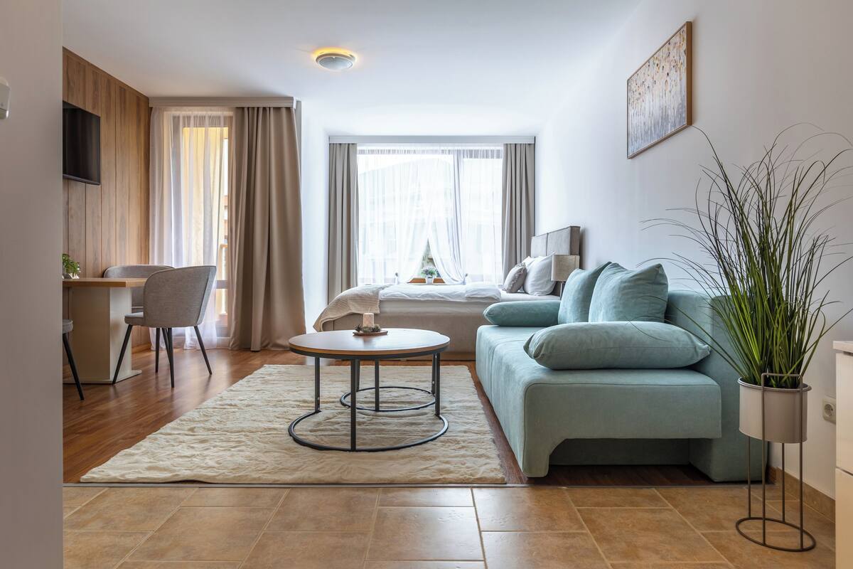 A modern living room with a sofa, a round coffee table, a desk, and a plant.