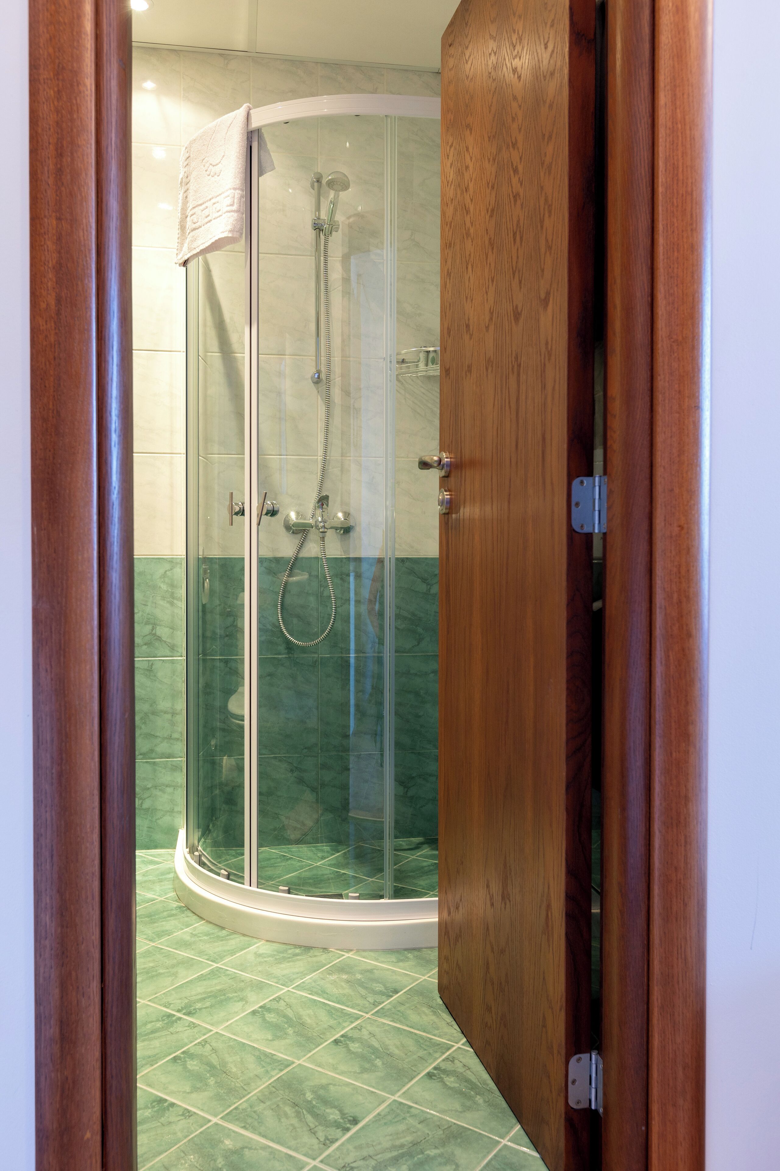 Une douche fermée par des parois en verre et dotée d’un cadre de porte en bois.