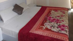 A bedroom with a bed, a pillow, and a red floral bedspread. - Oyo  The Jhunjhunu Palace Hotel (Jhunjhunu)