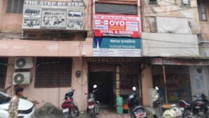 A building with multiple signs, including one for a hotel and rooms, and another for a step-by-step service. - Oyo  The Jhunjhunu Palace Hotel (Jhunjhunu)