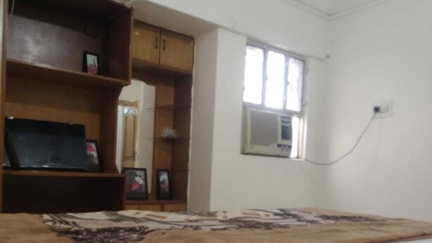 A bedroom with a bed, wooden wardrobe, and an air conditioning unit. - Oyo  The Jhunjhunu Palace Hotel (Jhunjhunu)