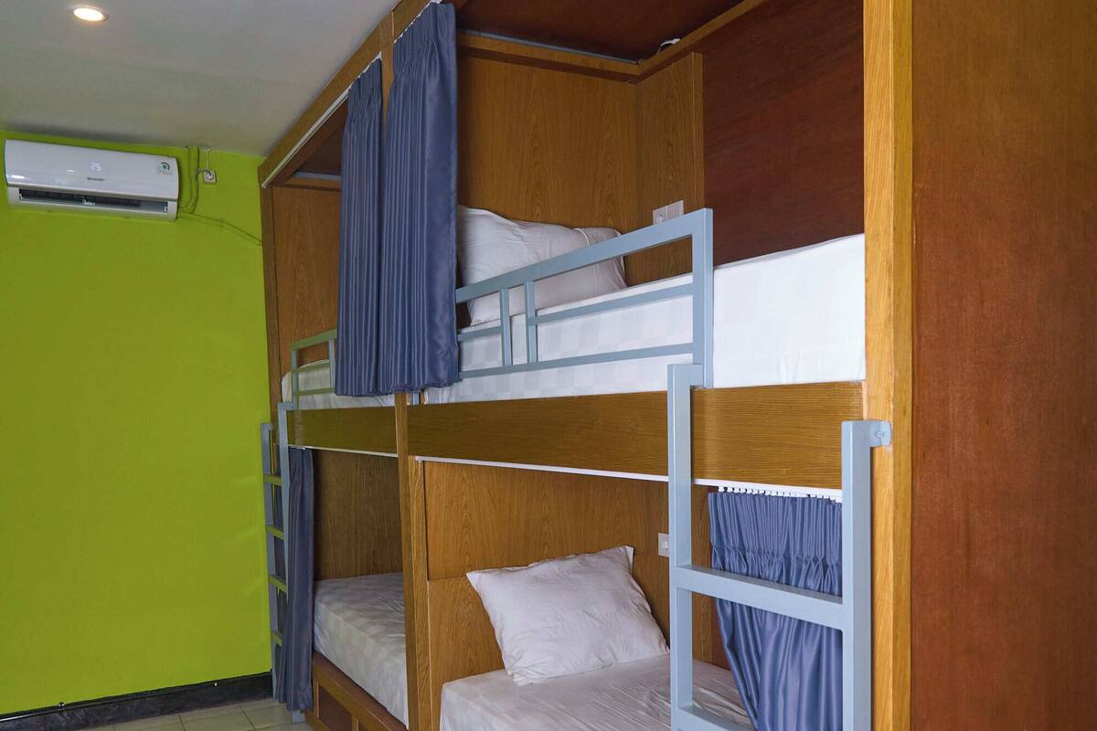 A bunk bed room with a wooden headboard, a ladder, and a window with curtains.