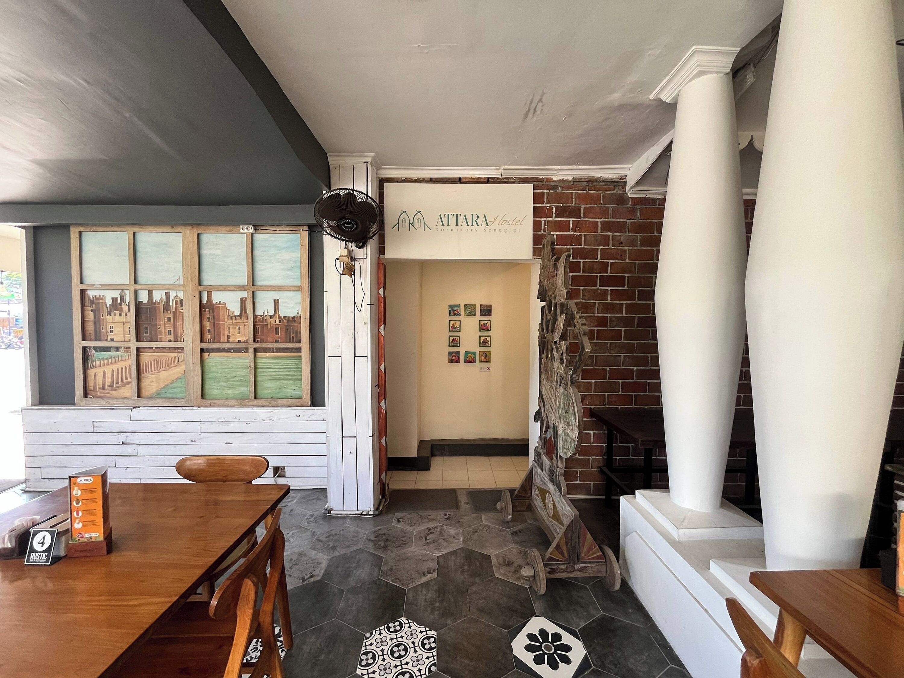 A hotel lobby with a wooden table, a vintage fan, a brick wall, and a sign reading 'ATARA Hotel'.